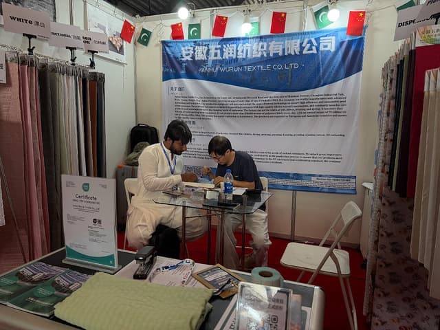 一位新结识的客户在展位上与我们的团队一起翻看样册、比对面料小样