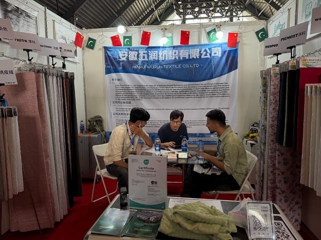 团队与一位来访买家详细沟通压花与双喷面料的规格与工艺